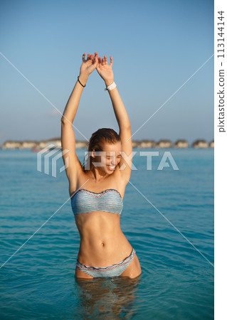 Pretty sexy beautiful woman in swimwear bikini posing in blue sea water. Model enjoys her vacation in ocean at exotic tropical island Pretty sexy beautiful woman in swimwear bikini posing in blue sea water. Model enjoys her vacation in ocean at exotic tropical island 113144144