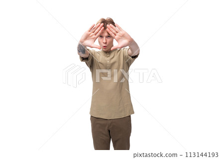 young caucasian guy dressed in khaki short sleeve shirt shows stop gesture young caucasian guy dressed in khaki short sleeve shirt shows stop gesture 113144193