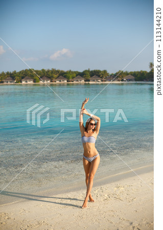 Spa wellness beach beauty woman in bikini swimwear relaxing and sun bathing near blue lagoon. Beautiful peaceful young female model on holiday travel tropical resort. Sun tan cream protection concept Spa wellness beach beauty woman in bikini swimwear relaxing and sun bathing near blue lagoon. Beautiful peaceful young female model on holiday travel tropical resort. Sun tan cream protection concept 113144210
