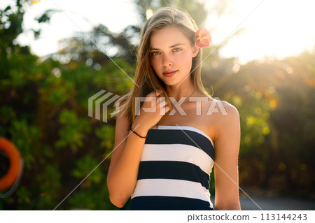 Spa wellness beach beauty woman relaxing andlooking at camera on beach. Beautiful serene and peaceful young female model on holiday travel resort enjoting vacation. Flower in braided hair Spa wellness beach beauty woman relaxing andlooking at camera on beach. Beautiful serene and peaceful young female model on holiday travel resort enjoting vacation. Flower in braided hair 113144243