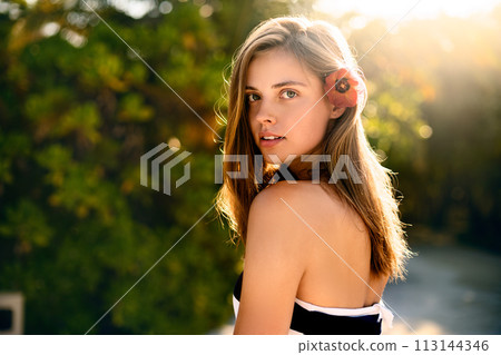 Spa wellness beach beauty woman relaxing andlooking at camera on beach. Beautiful serene and peaceful young female model on holiday travel resort enjoting vacation. Flower in braided hair 113144346