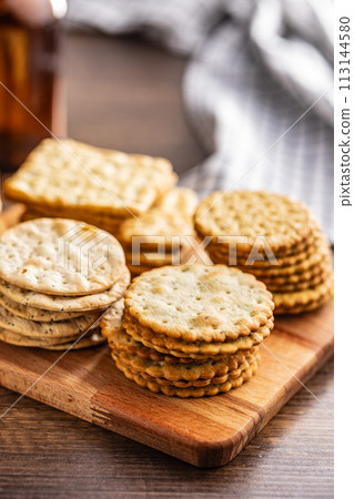 A stack of crackers neatly arranged on cutting board on wooden tabletop. 113144580