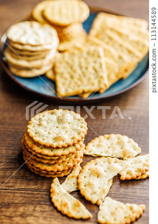 A stack of crackers neatly arranged on wooden tabletop. 113144589
