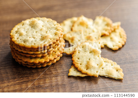 A stack of crackers neatly arranged on wooden tabletop. 113144590