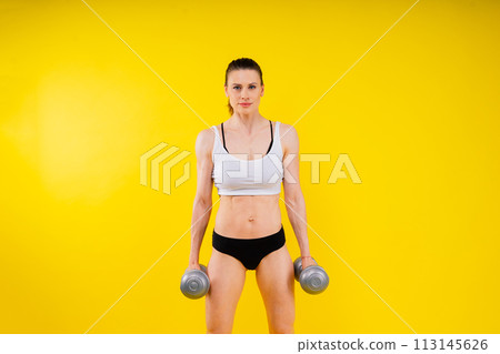 Woman training with dumbbells, pumping up muscles of hands and legs. Woman training with dumbbells, pumping up muscles of hands and legs. 113145626