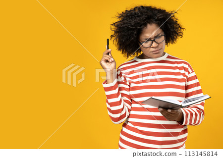 A young African American woman in glasses poses on a yellow background A young African American woman in glasses poses on a yellow background 113145814