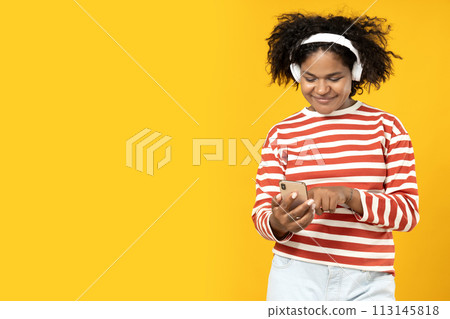 Young African American woman listening to music in headphones Young African American woman listening to music in headphones 113145818