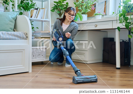 Middle aged female doing vacuuming at home Middle aged female doing vacuuming at home 113146144