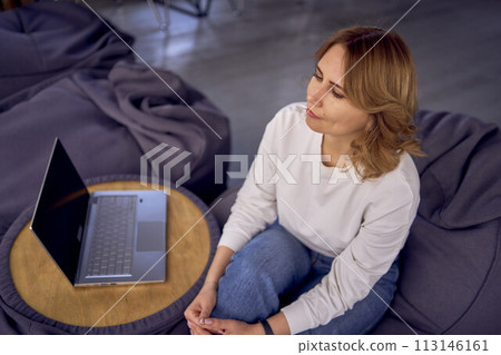 woman in casual clothes is working on a laptop on  bean bag 113146161