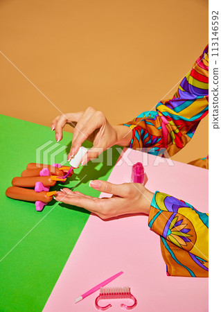 Creative colorful image of woman painting sausage nails against multicolored background, Beauty salon poster. 113146592