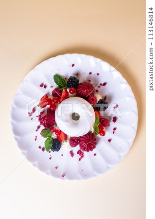 Dessert with white cream and fresh berries on a white plate. Isolated on a beige background Dessert with white cream and fresh berries on a white plate. Isolated on a beige background 113146814