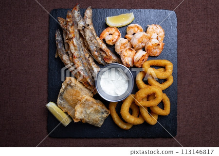 Top view of a delicious dish of fried seafood with shrimp, fish, squid and lemon slices 113146817