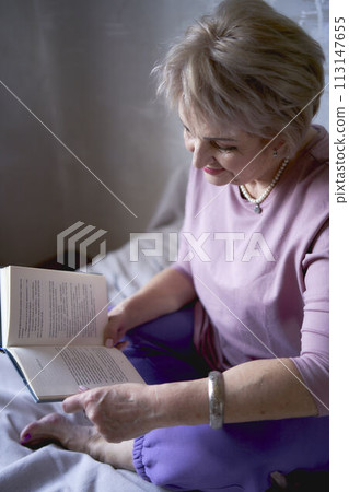 elderly woman reads a book at home 113147655