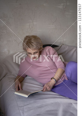 elderly woman reads a book at home 113147657