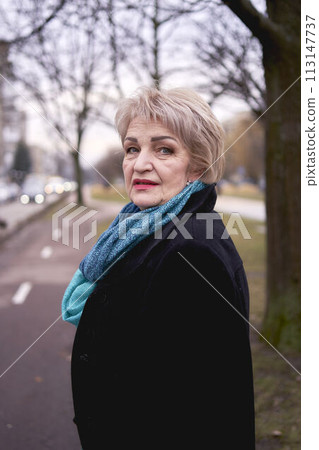 portrait of a stylish old woman in a black coat with green accessories on a spring street portrait of a stylish old woman in a black coat with green accessories on a spring street 113147737