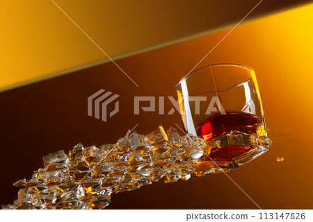 Whiskey with ice on a glass table. 113147826