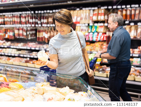 Elderly woman choose cheese in supermarket 113148137