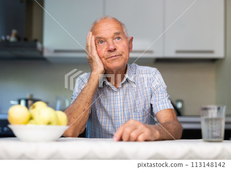 Senior man sitting at table in kitchen Senior man sitting at table in kitchen 113148142