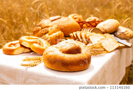 Lot of different flavored bread, wheat, rye, on the table in the field outside Lot of different flavored bread, wheat, rye, on the table in the field outside 113148160