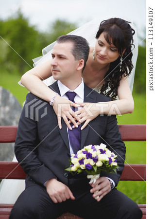 The brunette bride hugged the groom from behind on a summer day 113149107