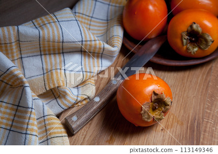 Whole ripe persimmon on a wooden background.. Whole ripe persimmon on a wooden background.. 113149346