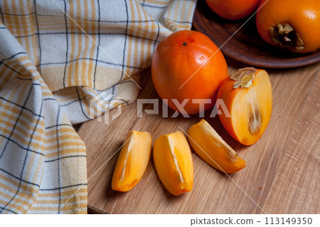 Whole ripe persimmon and sliced fruit on a wooden background.. Whole ripe persimmon and sliced fruit on a wooden background.. 113149350