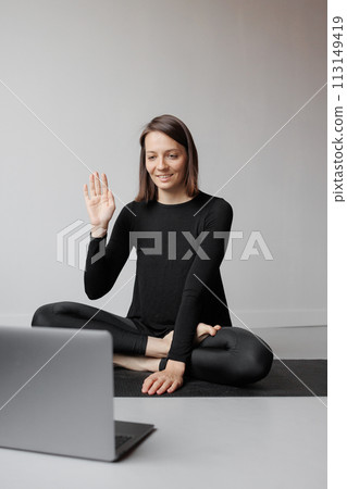 woman practicing yoga meditation gym, online video training with laptop with trainer on Internet.  113149419