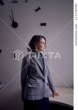 woman standing in office in front of clock 113149494
