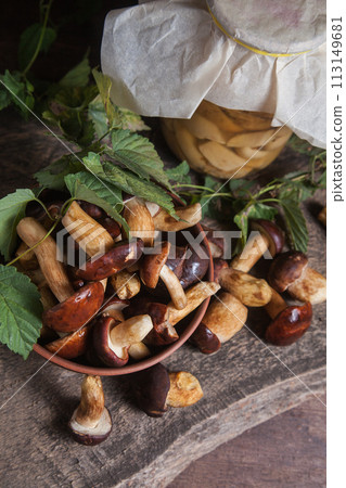Pile of Imleria Badia or Boletus badius mushrooms commonly known as the bay bolete with canned mushroom in glass jar on vintage wooden background.. 113149681