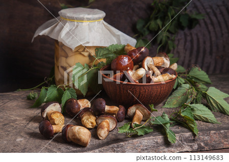 Pile of Imleria Badia or Boletus badius mushrooms commonly known as the bay bolete with canned mushroom in glass jar on vintage wooden background.. 113149683