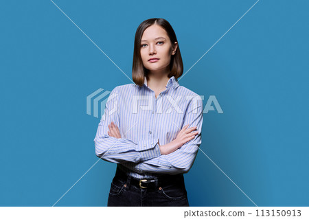 Young confident serious woman with crossed arms on blue background 113150913