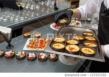 The waiter places snacks on the festive table 113151102
