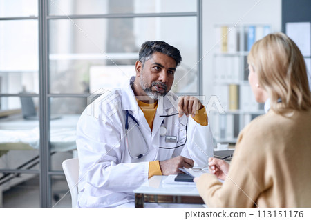 Portrait of attentive Middle Eastern doctor listening to female patient during consultation in clinic copy space 113151176