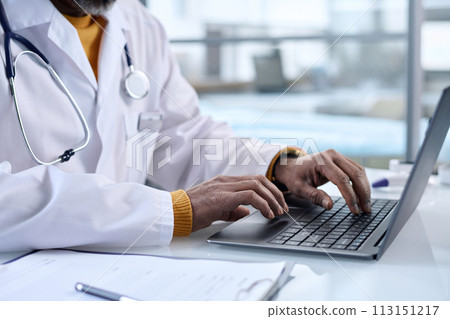 Side view closeup of unrecognizable doctor typing on laptop keyboard at workplace in clinic copy space 113151217