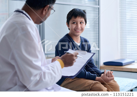 Portrait of smiling Middle Eastern boy looking at doctor during examination in medical clinic copy space Portrait of smiling Middle Eastern boy looking at doctor during examination in medical clinic copy space 113151221