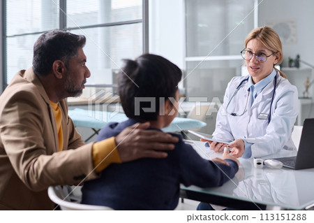 Portrait of caring female doctor consulting Middle Eastern family of father and son in clinic Portrait of caring female doctor consulting Middle Eastern family of father and son in clinic 113151288