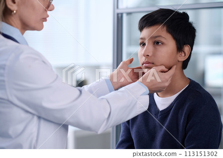 Portrait of young Middle Eastern boy in hospital with doctor examining neck and throat during checkup Portrait of young Middle Eastern boy in hospital with doctor examining neck and throat during checkup 113151302