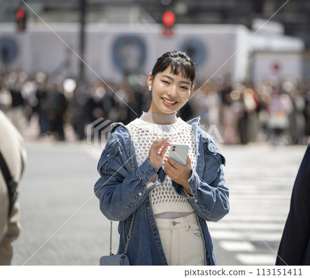 一位十幾歲的女人,拿著智慧型手機,看著鏡頭,微笑著 一位十幾歲的女人,拿著智慧型手機,看著鏡頭,微笑著 113151411