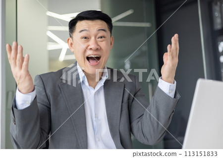 Joyous Asian man in business attire exuberantly celebrating a professional achievement inside a modern office space. Joyous Asian man in business attire exuberantly celebrating a professional achievement inside a modern office space. 113151833