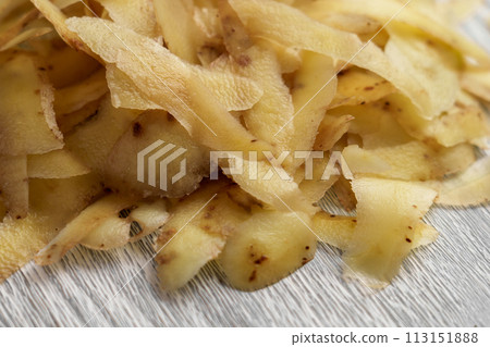 Pile of potato peels on a wooden cutting board close up Pile of potato peels on a wooden cutting board close up 113151888