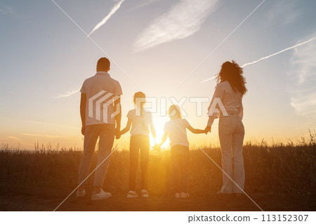 Happy family holding hands in field with plants at sunset. Happy family holding hands in field with plants at sunset. 113152307