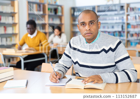 Young adult man studying in public library 113152687