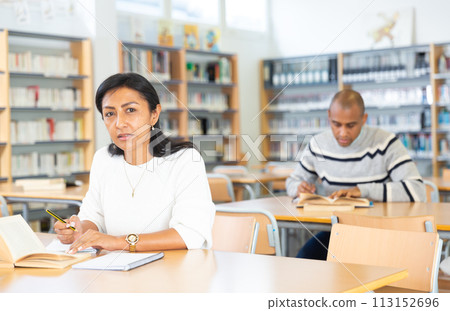 Concentrated hispanic woman reading books in public library Concentrated hispanic woman reading books in public library 113152696