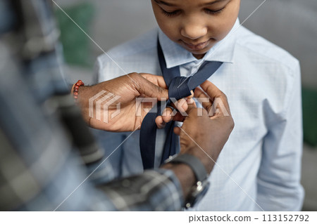 Close up of loving African American father tying tie for son first day of school Close up of loving African American father tying tie for son first day of school 113152792