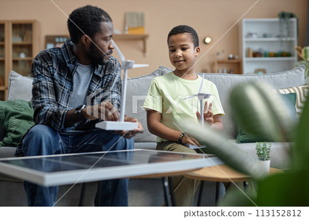 Portrait of African American father teaching son on renewable energy sources and holding wind turbine model 113152812