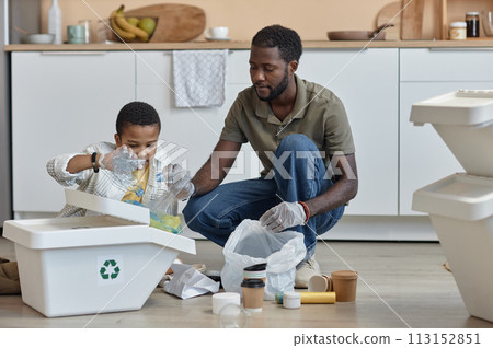 Full length portrait of African American father and son sorting paper and plastic for recycling at home Full length portrait of African American father and son sorting paper and plastic for recycling at home 113152851