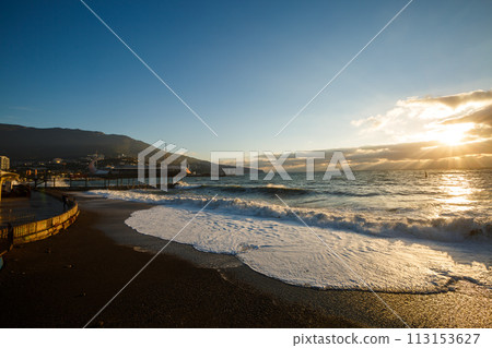 Storm at the sea and embankment street in the morning on. Big waves and tides wash against with lots of foam and splashes on sunrise. Storm at the sea and embankment street in the morning on. Big waves and tides wash against with lots of foam and splashes on sunrise. 113153627