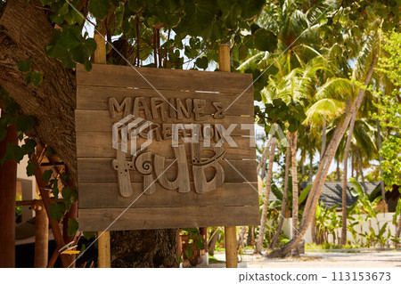 Marine recreation hub wooden sign with tropical palm trees on background Marine recreation hub wooden sign with tropical palm trees on background 113153673
