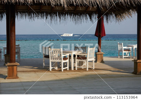 White empty table table and chairs at tropical resrraunt on open terrace in maldives. Blue ocean lagoon on background. No people. 113153964