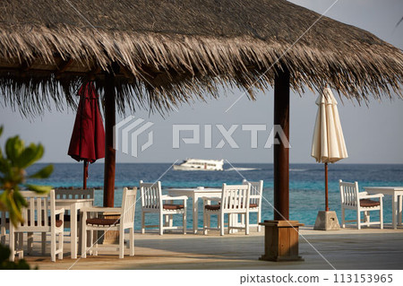 White empty table table and chairs at tropical resrraunt on open terrace in maldives. Blue ocean lagoon on background. No people. 113153965